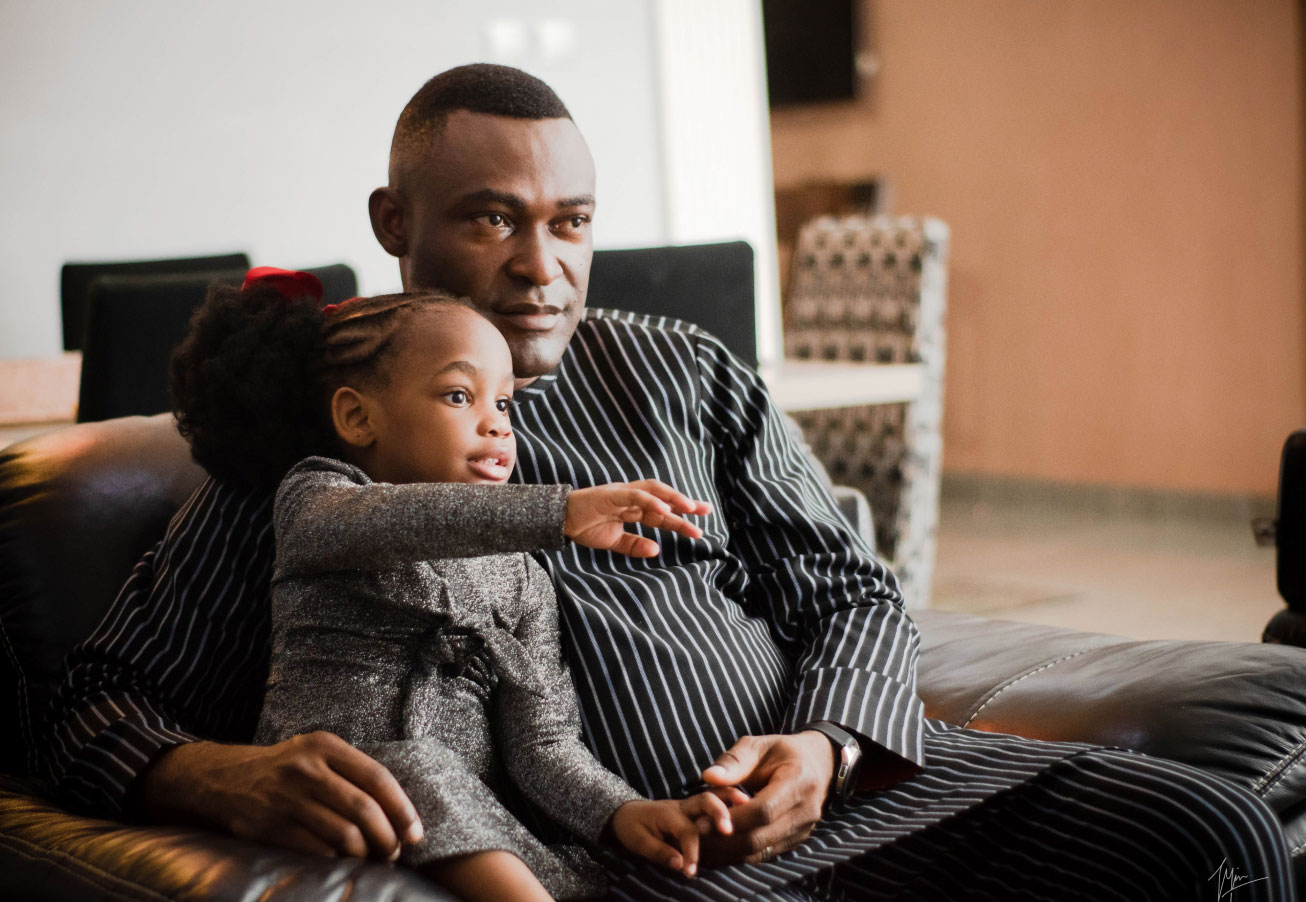 father figure with young girl looking at a television or something similar in a living room setting